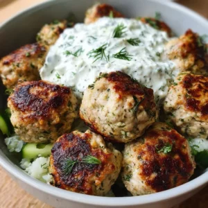 Plate of Greek chicken meatballs with homemade tzatziki sauce and fresh herbs.