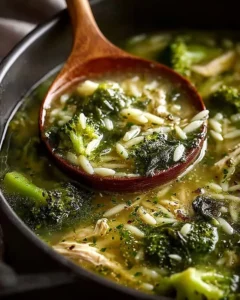 Delicious bowl of Broccoli Chicken Orzo Soup with Spinach garnished with herbs.